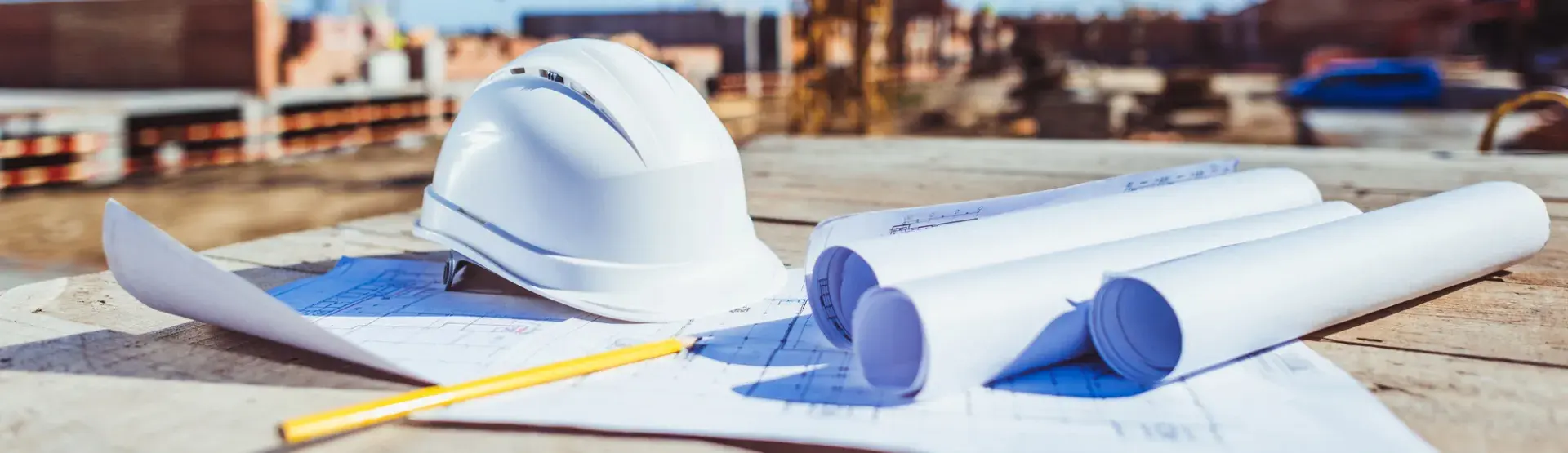 Hard hat with tape measure and design plans