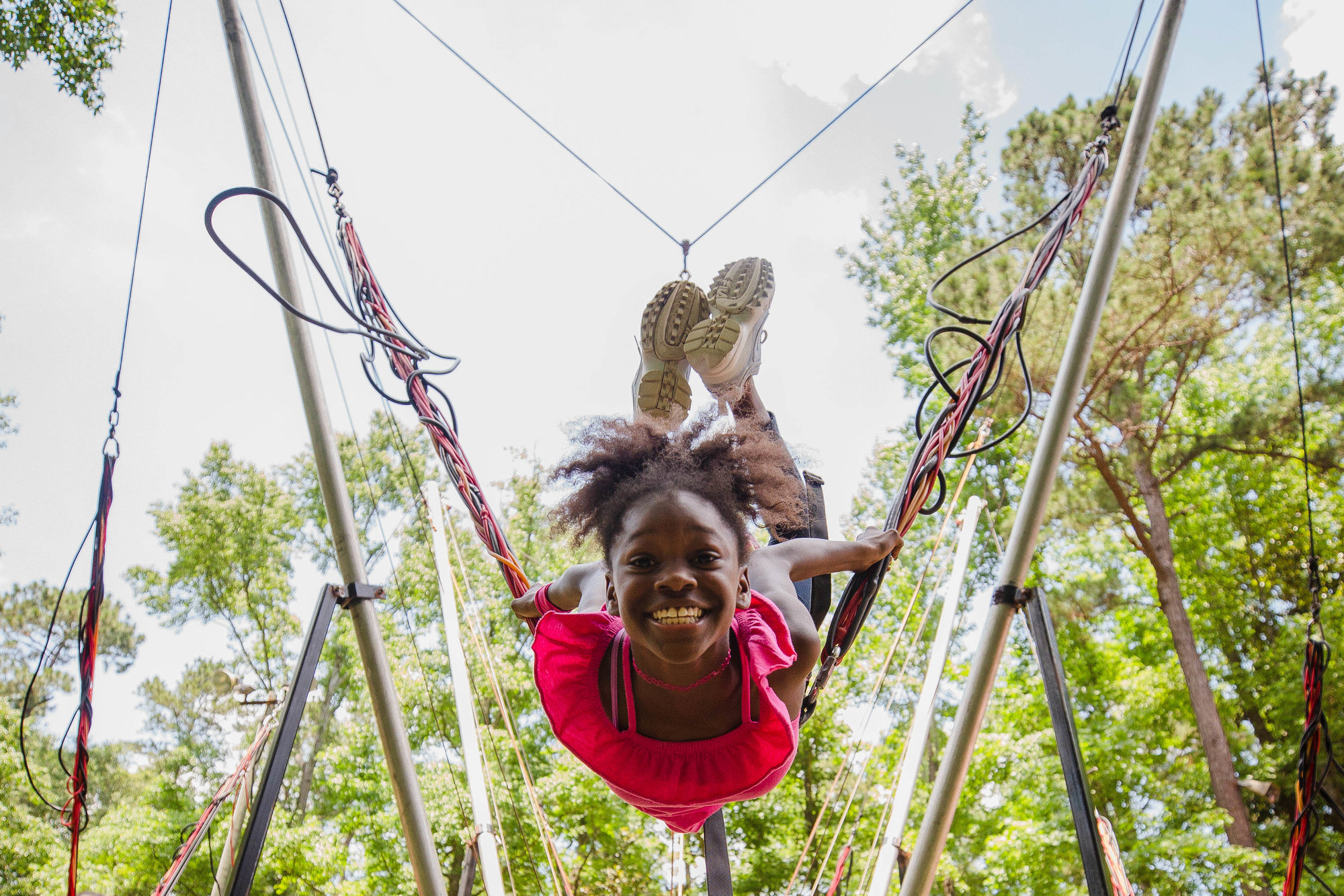 Young girl with huge smile bouncing on bungee cords