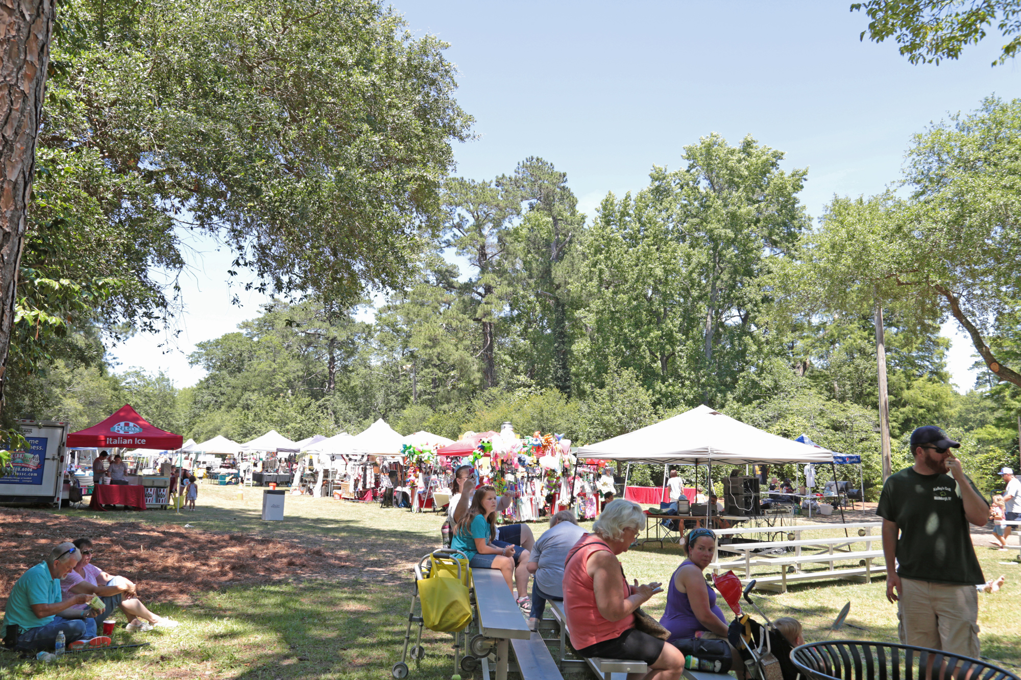 People eating and resting in front of fair ground tents